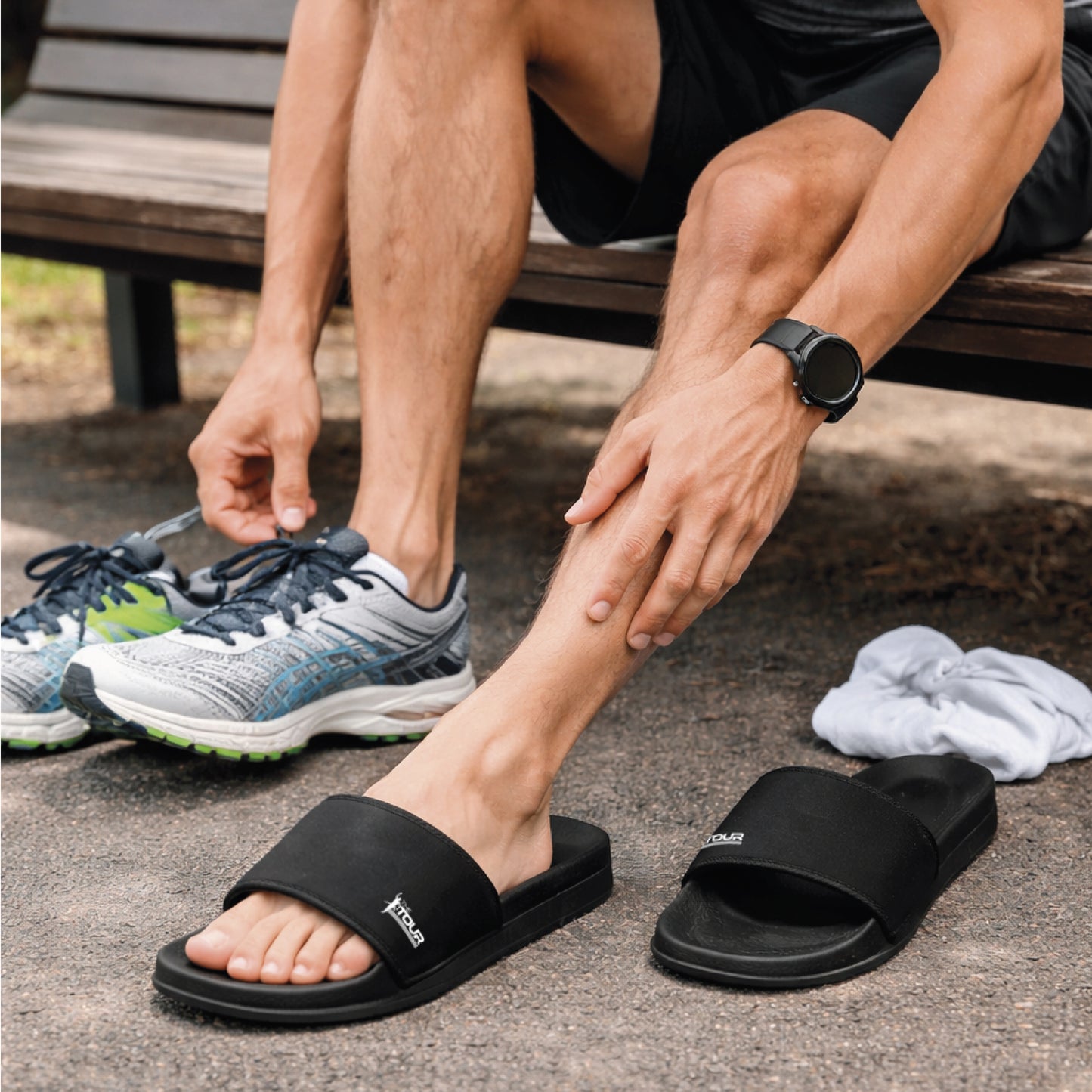 Person wearing black slides and switching to running shoes outdoors.